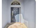 Gray front door with glass sidelights, leading into the home at 11644 Spindrift Loop, Hudson, FL 34667