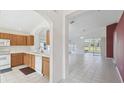 Kitchen with oak cabinets, white appliances, and view into living area at 11644 Spindrift Loop, Hudson, FL 34667