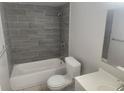 Updated bathroom with gray tile and a new bathtub at 12804 Waterbury Ave, Hudson, FL 34669