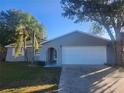 Gray house with a white garage door and landscaped lawn at 12804 Waterbury Ave, Hudson, FL 34669