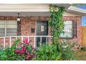 Close-up of the front door, with decorative ironwork, vines, and lush landscaping at 4939 18Th St, Zephyrhills, FL 33542