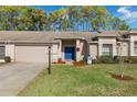 Tan brick home with a blue front door, nicely landscaped lawn, and a snowman decoration at 7423 Woodhollow Rd, Spring Hill, FL 34606