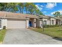 Tan brick home with attached garage, landscaped lawn, and a snowman decoration at 7423 Woodhollow Rd, Spring Hill, FL 34606