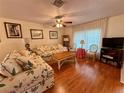 Living room featuring floral sofas, wood floors, and a ceiling fan at 8704 Winding Wood Dr, Port Richey, FL 34668