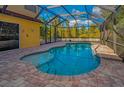 Inviting screened-in pool area featuring a sparkling pool and brick-paved patio for relaxation and entertainment at 11645 Belle Haven Dr, New Port Richey, FL 34654