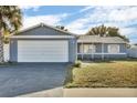 Charming single Gathering home with an attached garage, manicured lawn, and covered front porch entry at 15950 Adobe Dr, Hudson, FL 34667