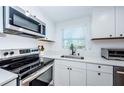 Modern kitchen boasts stainless steel appliances, white shaker cabinets, and sleek countertops at 3444 Clydesdale Dr, Holiday, FL 34691