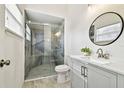 Modern bathroom with a glass shower, white vanity, and a round mirror at 7717 Foxbear Ct, New Port Richey, FL 34655