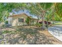 Tan house with brown roof, landscaping, and driveway, view from the side at 3049 Moog Rd, Holiday, FL 34691