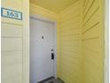 Condo building entry with a white door and yellow siding at 455 Alt 19 S # 163, Palm Harbor, FL 34683