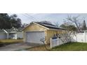 Rear exterior view of the house showcasing a detached garage with solar panels and a white picket fence at 5031 6Th N Ave, St Petersburg, FL 33710