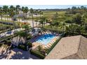 Community pool area featuring a covered lounge area, jacuzzi and sun loungers surrounded by palm trees at 14120 Whitecap Ave, Hudson, FL 34667