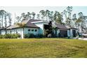 A modern home with dark roof, wood accents and a lush green lawn surrounded by tall trees at 12149 Chapman Ave, Port Charlotte, FL 33953