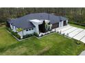 Aerial view of a modern home with dark roof, lush lawn, and a two-car garage at 12149 Chapman Ave, Port Charlotte, FL 33953