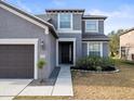 Close-up of a gray two-story home featuring an attached garage and trimmed front yard at 14143 Wake Robin Dr, Brooksville, FL 34604