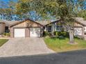 Lovely single-story home with a brick driveway, two-car garage, well-maintained lawn, and mature trees at 7414 Heather Walk Dr, Weeki Wachee, FL 34613
