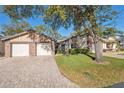 Charming single-story home with a brick driveway, two-car garage and mature trees at 7414 Heather Walk Dr, Weeki Wachee, FL 34613