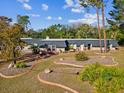 A ranch-style home has meticulously landscaped front yard with decorative garden beds and mature trees at 7815 Tanglewood Dr, New Port Richey, FL 34654
