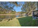 Serene backyard featuring a pond, mature trees, and lush green lawn extending to the water's edge at 11243 Merganser Way, New Port Richey, FL 34654