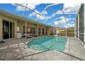 A refreshing in-ground pool is encased in a screened enclosure with an outdoor living space at 14215 Presteign Ln, Spring Hill, FL 34609