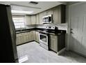 Well-lit kitchen with stainless steel appliances, granite counters and grey shaker cabinets at 5641 Quist Dr, Port Richey, FL 34668