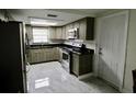 Well-lit kitchen with stainless steel appliances, gray cabinets, and gray tile flooring at 5641 Quist Dr, Port Richey, FL 34668