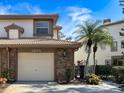 Townhouse exterior featuring a two-car garage, brick accents, tile roof, and well-maintained landscaping at 1203 Clays Trl # 406, Oldsmar, FL 34677