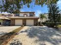 Inviting townhouse exterior showing two-car garage, brick accents, tile roof, and mature landscaping at 1203 Clays Trl # 406, Oldsmar, FL 34677