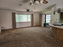 Open floor plan featuring a carpeted living room with a ceiling fan and sliding door access to the backyard at 12501 Shadow Ridge Blvd, Hudson, FL 34669