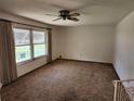 Bright living room with large window, neutral walls, carpeted flooring, and a ceiling fan at 12501 Shadow Ridge Blvd, Hudson, FL 34669