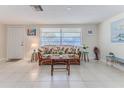 Bright living room featuring tile flooring, a cozy wicker sofa, and ample natural light at 13705 Allyn Dr, Hudson, FL 34667