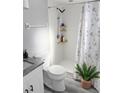 Cozy bathroom features a shower with floral curtain and a wood shelf for toiletries near the toilet at 4218 San Rafael Ave, New Port Richey, FL 34655