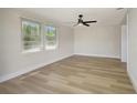 Bright bedroom featuring hardwood floors, white walls, a ceiling fan, and natural light from the windows at 1888 Douglas Ave, Dunedin, FL 34698