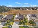 Aerial view of a single-story home with solar panels, a landscaped yard and a lush field in the background at 2109 Trillium Blvd, Brooksville, FL 34604