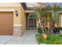 Home's inviting front entry featuring a screened front door, stacked stone details, and lush landscaping at 2109 Trillium Blvd, Brooksville, FL 34604