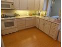 Traditional white kitchen with updated appliances and wood-look flooring at 4801 Airport Rd # 208, Zephyrhills, FL 33542