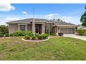 Charming single-story home features a well-manicured lawn, colorful foliage, and a screened garage at 6112 Kinlock Ave, Spring Hill, FL 34608