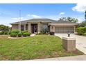 Charming single-story home features a well-manicured lawn, colorful foliage, and a screened garage at 6112 Kinlock Ave, Spring Hill, FL 34608
