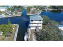 An aerial view showcasing a waterfront home with a boat dock and neighborhood canals at 6801 Nowiki Ave, Hudson, FL 34667