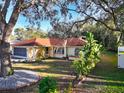 Quaint single-story home with a red tile roof, framed by mature trees and lush landscaping at 5518 Pinehurst Dr, Spring Hill, FL 34606