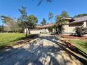 Inviting front exterior with well-maintained landscaping and a long driveway at 7090 Red Oak Loop, New Port Richey, FL 34654