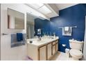 Full bathroom showing blue accent wall, vanity with sink, toilet and tiled floors, and a shower at 11725 Spring Tree Ln, Port Richey, FL 34668