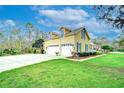 This home features a spacious driveway leading to a three-car garage and well-maintained lawn at 1031 Pomme De Pin Ln, New Port Richey, FL 34655