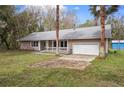 View of this single Gathering home featuring an attached garage, well manicured lawn and mature palm trees at 13289 Joy Path, Brooksville, FL 34601