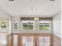 Bright living room featuring hardwood floors, large windows, and elegant chandelier at 18325 Whitacre Cir, Hudson, FL 34667