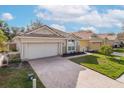 Well-maintained home featuring a brick driveway, stone accents, and manicured lawn at 4412 Caliquen Dr, Brooksville, FL 34604