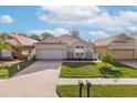 Well-maintained home featuring a brick driveway, stone accents, manicured lawn and blue sky at 4412 Caliquen Dr, Brooksville, FL 34604