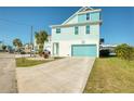 Inviting coastal home with a turquoise garage door and a spacious stamped concrete driveway at 6613 Josie Ln, Hudson, FL 34667