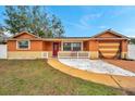 Inviting single-story home featuring a bright red front door and well-manicured lawn at 9220 Saint Regis Ln, Port Richey, FL 34668