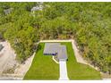 Aerial view of a home nestled in a forest, featuring a well-kept lawn and long driveway at 11345 Thrasher Ave, Weeki Wachee, FL 34614